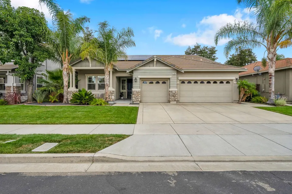 Front view of 173 Pescara Boulevard with palm trees, lawn, covered porch and three-car garage.