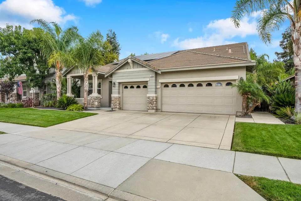 Angled view across the driveway toward the attached three-car garage and covered front entry.