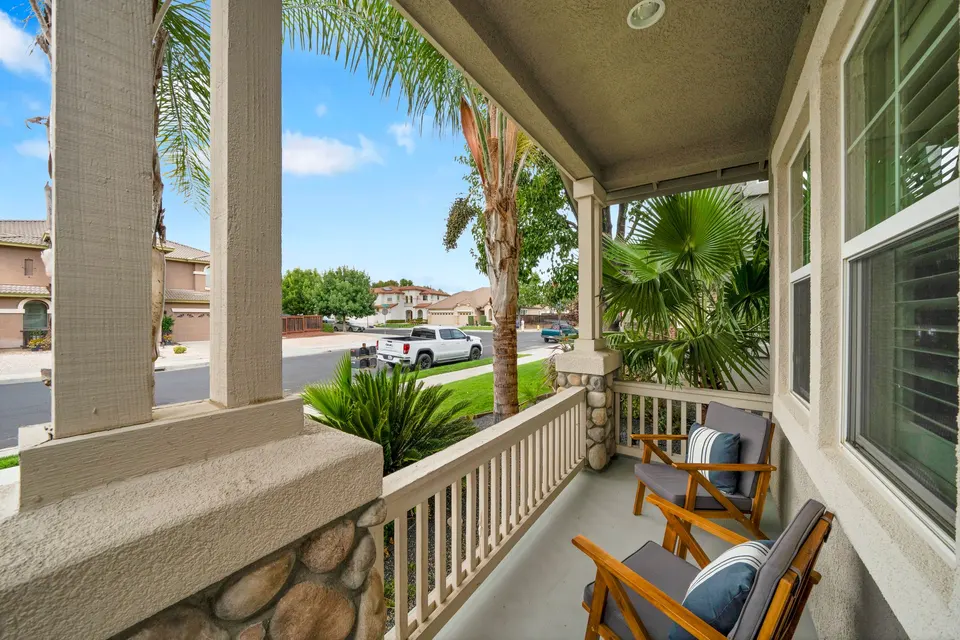Covered front porch with chairs, stone-accented columns and a view toward Pescara Boulevard.