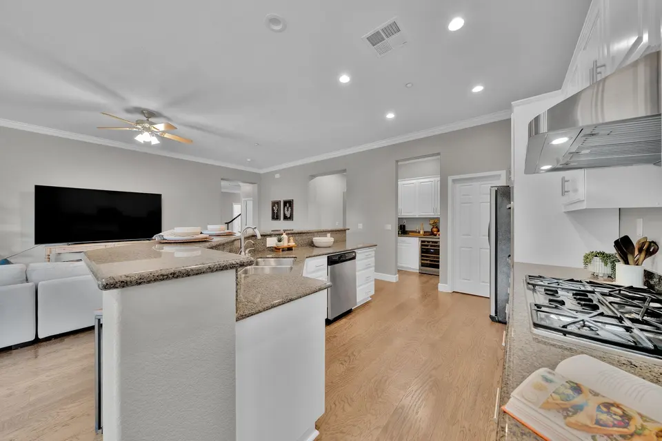 Kitchen with a gas cooktop and stone-topped breakfast bar facing the open family room.