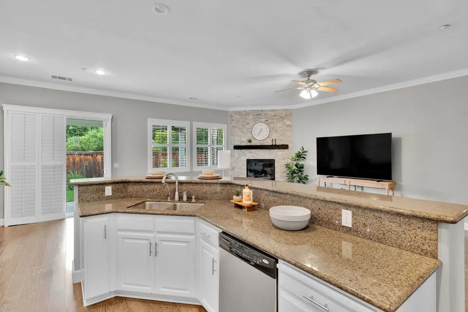 Stone kitchen counters and sink beside a raised bar overlooking the family room fireplace.