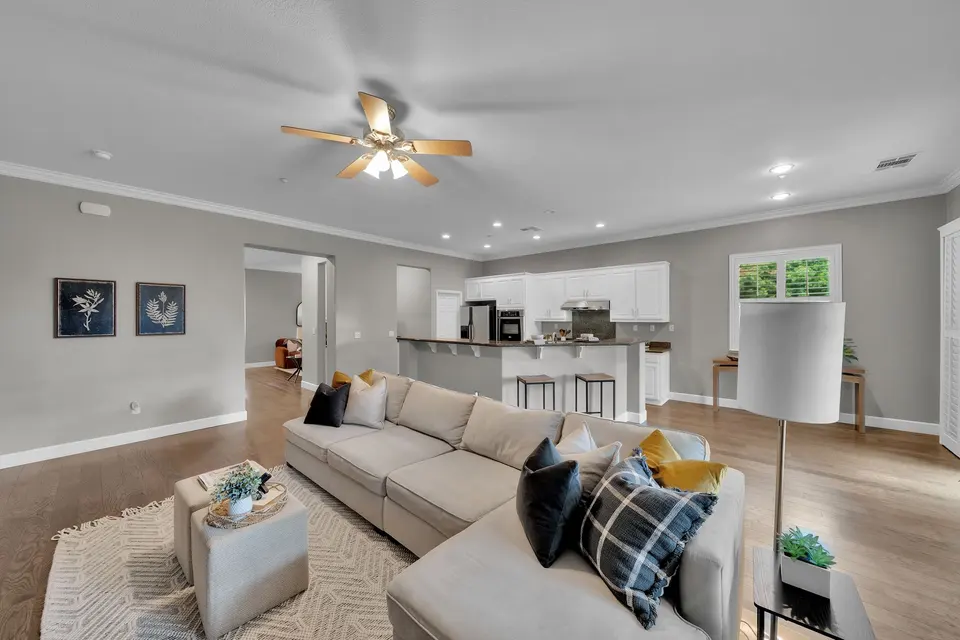 Family room sofa and open kitchen with a breakfast bar and white cabinetry beyond.