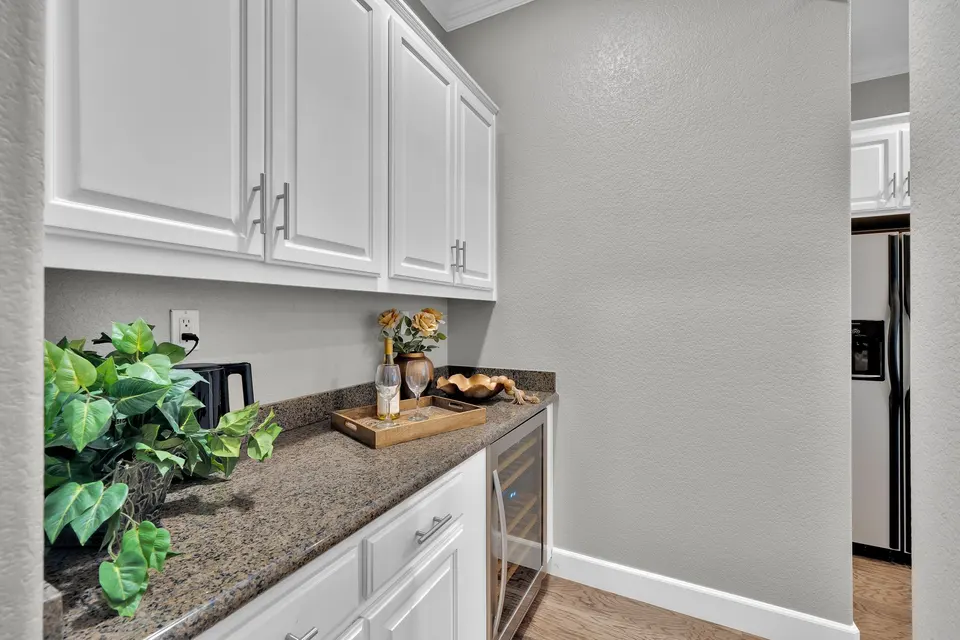 Separate serving counter with white cabinets and an under-counter wine refrigerator.