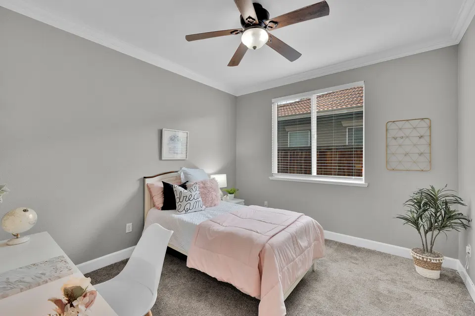 Secondary bedroom with a window, ceiling fan and space arranged with a single bed and desk.