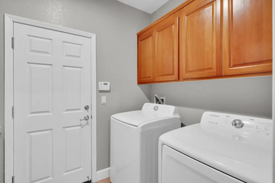 Laundry room with washer, dryer and overhead wood storage cabinets.