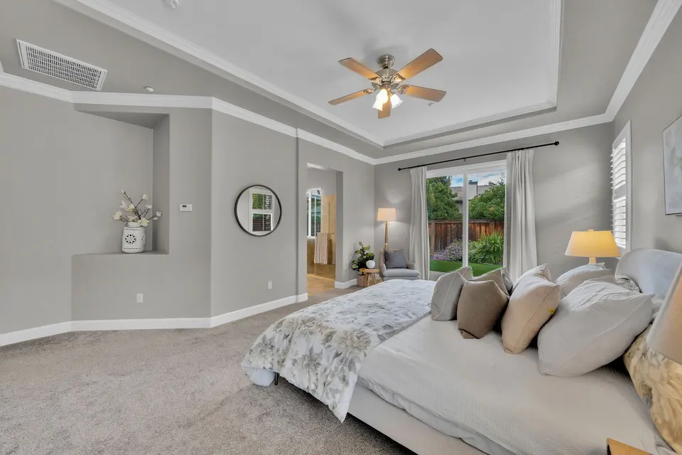Primary bedroom seating area and sliding glass door opening toward the landscaped backyard.