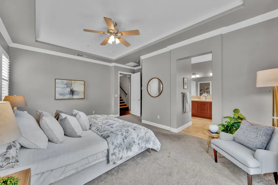 Primary bedroom with a tray ceiling and an open entry to its adjoining bathroom.