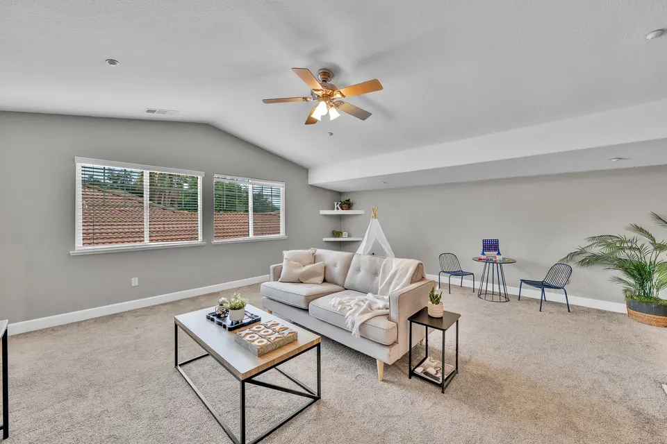 Wide upstairs loft with a sitting area, windows and additional flexible floor space.