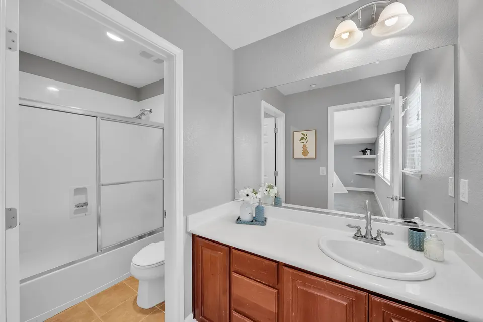 Bathroom adjoining the loft with a wood vanity, toilet and glass-enclosed shower.