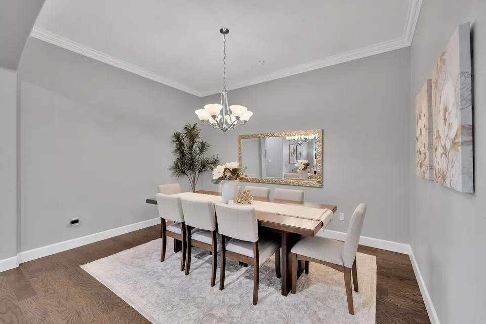 Dining room with a rectangular table beneath a chandelier and a broad opening to the living area.
