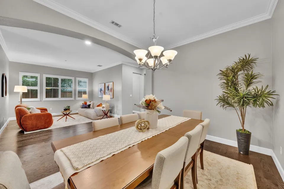 Dining room table and chandelier with the front living room visible through the broad opening.