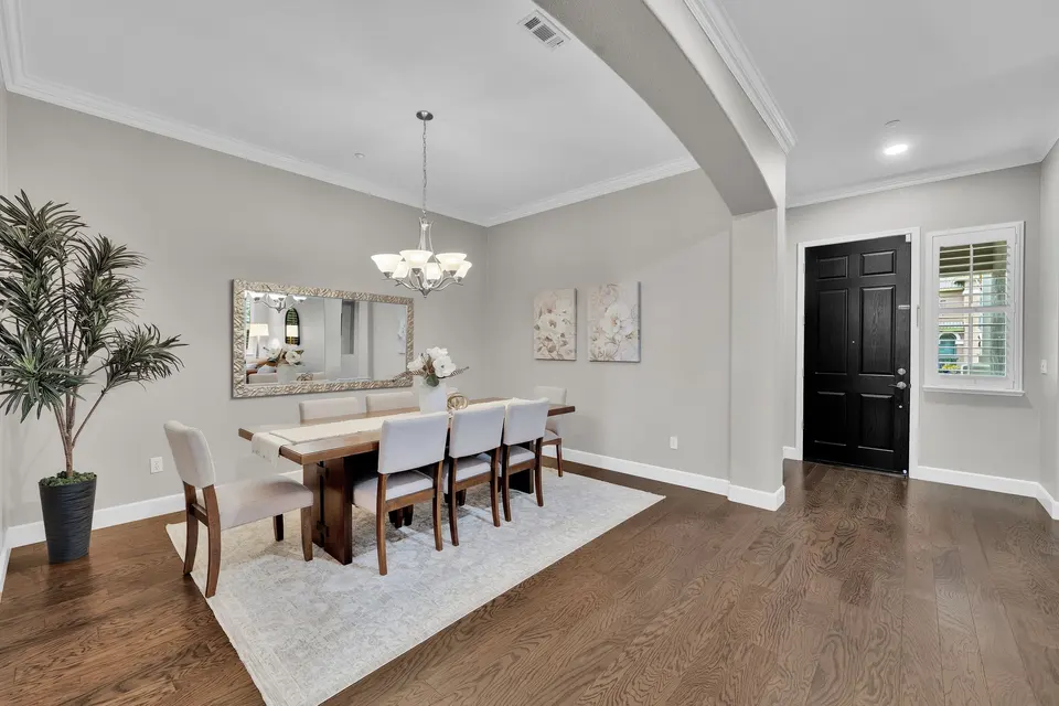 Dining area beside the entry door, with a chandelier and view into the front living space.